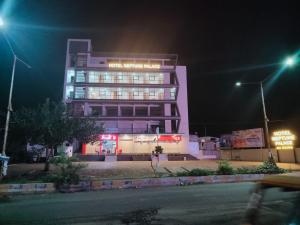 ein hohes Gebäude mit Lichtern in der Nacht davor in der Unterkunft Hotel Neptune Palace in Anand