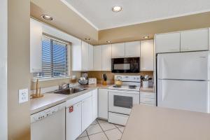 uma cozinha com armários brancos e um frigorífico branco em Sandpiper Cove 2133 Condo em Destin