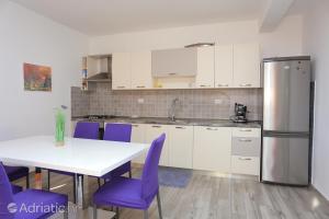 a kitchen with a table and purple chairs and a refrigerator at Apartments Luciano in Seget Vranjica