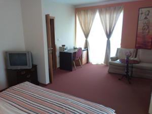 a bedroom with a bed and a tv and a couch at Hotel Lukavac in Lukavac