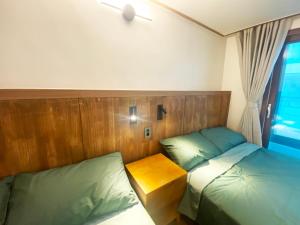 1 Schlafzimmer mit 2 Betten und einem Kopfteil aus Holz in der Unterkunft Luxe & Suite Room in Seoul