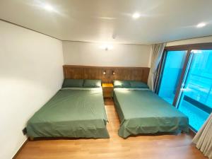 2 Betten in einem kleinen Zimmer mit Fenster in der Unterkunft Luxe & Suite Room in Seoul