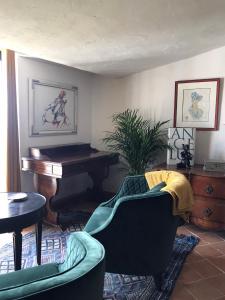 - un salon avec un piano et une chaise verte dans l'établissement Derrière l'église, à Saint-Paul-de-Vence