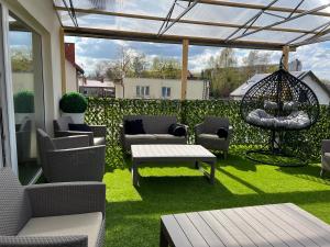 a patio with chairs and a swing and grass at Comfort Zone Ostróda Villa Apartment B in Ostróda