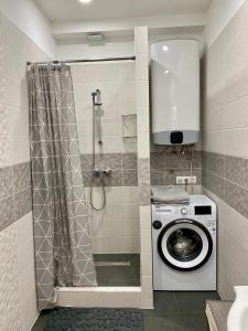 ein Bad mit einer Dusche und einer Waschmaschine in der Unterkunft Sasfeszek Apartman (Teljes lakás) in Szeged