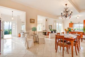 a dining room and living room with a table and chairs at Villa Rosemagnolia, pool 35m2, in green, gardens, full sun close to everything in Ayiá