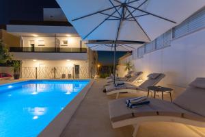 a swimming pool with lounge chairs next to a building at Villa Fortis B&B in Trogir
