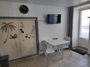 a dining room with a table and chairs and a clock at Studio 2 personnes en centre ville in Saint-Pierre-de-Plesguen