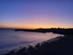 - une vue sur la plage au coucher du soleil dans l'établissement Front de mer vue exceptionnelle, à Granville