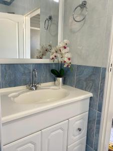 a bathroom sink with a vase with flowers in it at Sea View Penthouse in Ballito