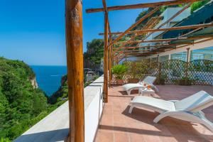 Un balcón con sillas blancas y vistas al océano. en Hotel La Pergola, en Amalfi