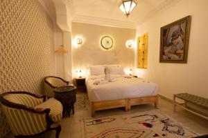 a bedroom with a white bed and two chairs at Riad El Habib in Marrakech