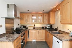 a kitchen with wooden cabinets and stainless steel appliances at Idyllic Cottage near Padstow in Little Petherick
