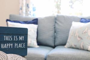 a living room with a gray couch with a happy place sign at Idyllic Cottage near Padstow in Little Petherick