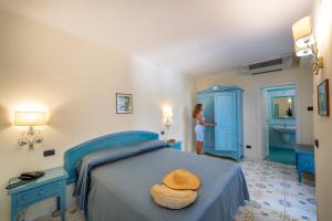 Eine Frau steht in einem Schlafzimmer mit einem blauen Bett in der Unterkunft Hotel La Pergola in Amalfi