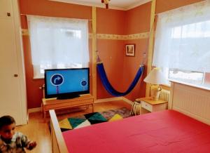 a child in a bedroom with a television and a bed at Bedroom private, 120 from Sandbach in Bräcke
