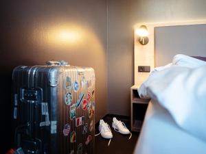 une chambre d'hôtel avec une valise et des paires de chaussures dans l'établissement aletto Hotel Kudamm, à Berlin