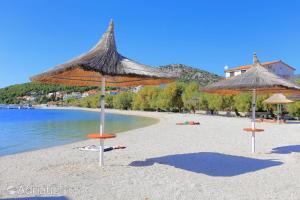 a beach with umbrellas and chairs and the water at Apartments Luciano in Seget Vranjica