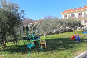 un patio con un parque infantil con un columpio en Apartments Luciano, en Seget Vranjica