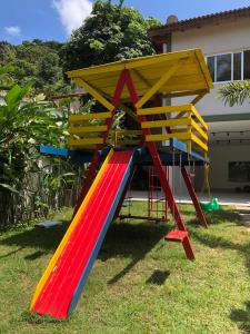 a playground with a colorful slide in a yard at Casa Piscina AQUECIDA PRIVATIVA Serv Praia Condom Fechado! in São Sebastião