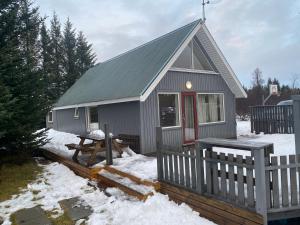 a small house with a fence in the snow at A three bedroom cabin with a hot tub in Selfoss
