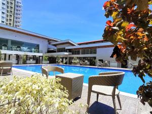 a swimming pool with tables and chairs next to a building at Pool View Studio in Mesaverte with Free Pool & Netflix in Cagayan de Oro
