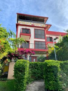 un grand bâtiment rouge avec des buissons devant lui dans l'établissement Buena Vista Boquete, à Boquete