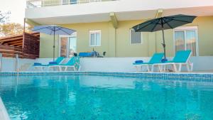 a swimming pool with blue chairs and umbrellas at Greek Style Ground Floor Apartment & Pool in Ialysos