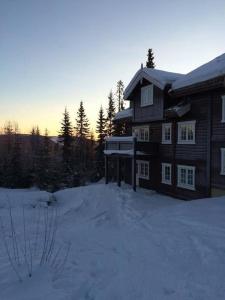 a house in the snow with the sun setting behind it at Flat in Trysil Ski in ski out and sauna in Trysil