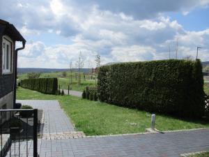 a hedge next to a walkway next to a house at Ferienwohnung Ritha in Sandberg
