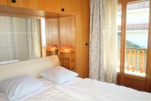 een slaapkamer met een bed en een raam met een balkon bij Iris CONFORTABLE & PLEASANT apartments by Alpvision Résidences in Veysonnaz