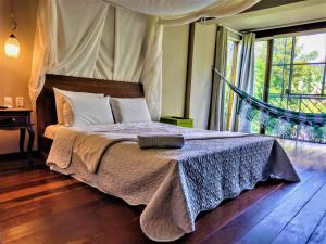 a bedroom with a bed with a blanket and a window at Pousada Zazen in Vale do Capao