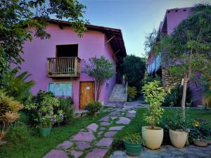een roze huis met een loopbrug ervoor bij Pousada Zazen in Vale do Capao