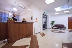 a man and woman standing at a reception desk in a lobby at Zajazd Trzy Dęby in Janów