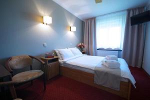 une chambre d'hôtel avec un lit, une chaise et une fenêtre dans l'établissement Zajazd Trzy Dęby, 