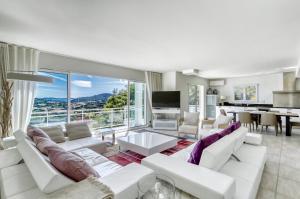 uma sala de estar com mobiliário branco e uma grande janela em Beautiful contemporary villa with sea view, heated swimming pool, near Saint Tropez em Cavalaire-sur-Mer