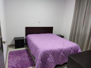 um quarto com uma cama roxa com lençóis roxos e 2 tapetes em Casa de férias e fins de semana,1 em Esposende