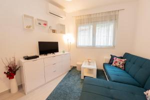 a living room with a blue couch and a tv at Apartment Peace in Kotor