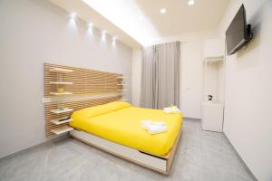 a bedroom with a yellow bed and a television at Houses & Rooftop Pompei - Sky in Pompei +83 photos