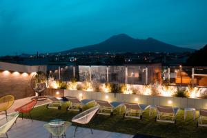 a rooftop patio with chairs and lights at night at Houses & Rooftop Pompei - Sky in Pompei