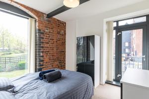 - une chambre avec un lit et un mur en briques dans l'établissement Clock Towers, 2 Bed, Stockton Heath, Warrington, Parking, à Warrington