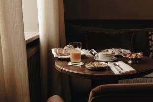 a table with food and a glass of orange juice at Parkhotel Mondschein, a Member of Design Hotels in Bolzano