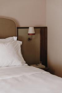 a bed with a white pillow and a lamp on a table at Parkhotel Mondschein, a Member of Design Hotels in Bolzano