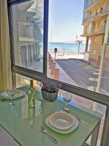 a table with a plate and wine glasses in front of a window at Apartamento Bajo 3 Dúplex Marjal playa centro de Guardamar in Guardamar del Segura
