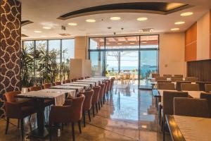 a row of tables and chairs in a room with windows at Hotel & Apartments HEC Residence in Sveti Stefan
