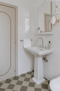a white bathroom with a sink and a mirror at Parkhotel Mondschein, a Member of Design Hotels in Bolzano