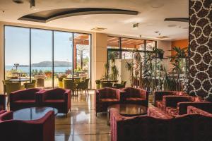 a waiting room with chairs and tables and windows at Hotel & Apartments HEC Residence in Sveti Stefan