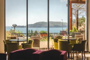 a restaurant with tables and chairs and a view of the water at Hotel & Apartments HEC Residence in Sveti Stefan