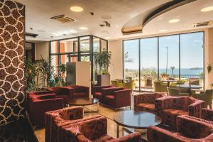 a waiting room with chairs and tables and windows at Hotel & Apartments HEC Residence in Sveti Stefan