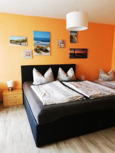 a bedroom with a bed with an orange wall at Ferienhäuser Steffi und Ruth in Ueckeritz